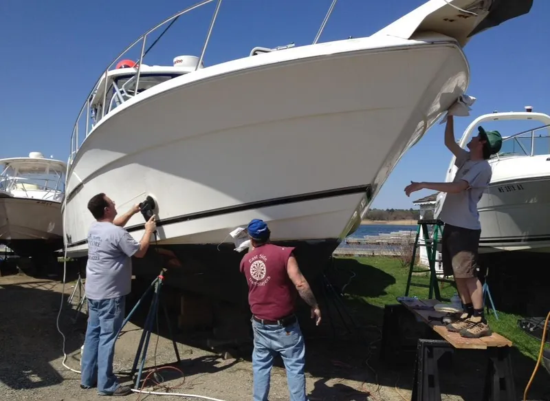 Slide: The Image of Men cleaning and polishing a 2000 Wellcraft 330 Coastal boat on land. - 4
