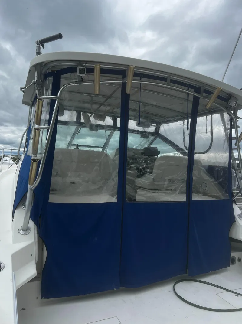 Slide: The Image of 2000 Wellcraft 330 Coastal boat with blue canopy under cloudy sky. - 6