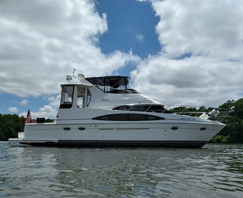Slide: The Image of 2001 Carver 444 Cockpit Motor Yacht on a calm lake under a partly cloudy sky. - 0