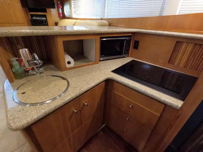 Slide: The Image of Compact kitchen area in a 2001 Carver 444 Cockpit Motor Yacht with sink, stove, and microwave. - 48