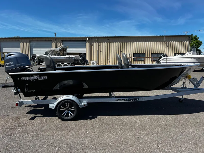 Slide: The Image of 2024 Fish Rite Angler boat on trailer, parked outdoors near a warehouse. - 13