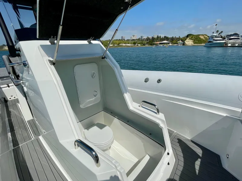Slide: The Image of 2024 Northstar Orion 8 boat with open toilet compartment, docked near a scenic coastline. - 10