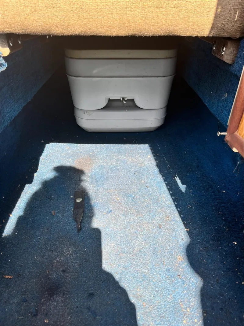 Slide: The Image of 1988 Sea Ray Sierra interior with portable toilet on blue carpet. - 7