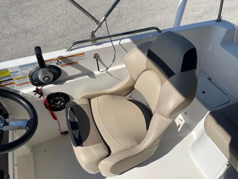 Slide: The Image of Captain's seat on 2021 Hurricane SunDeck Sport 201 OB boat, featuring beige upholstery and steering controls. - 19