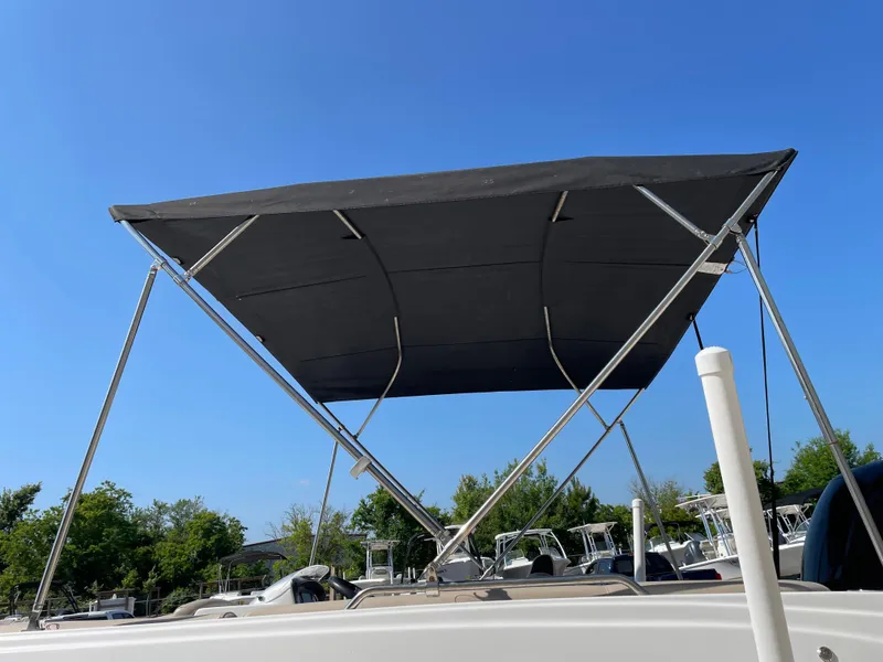 Slide: The Image of 2021 Hurricane SunDeck Sport 201 OB boat with a black bimini top under clear blue sky. - 26