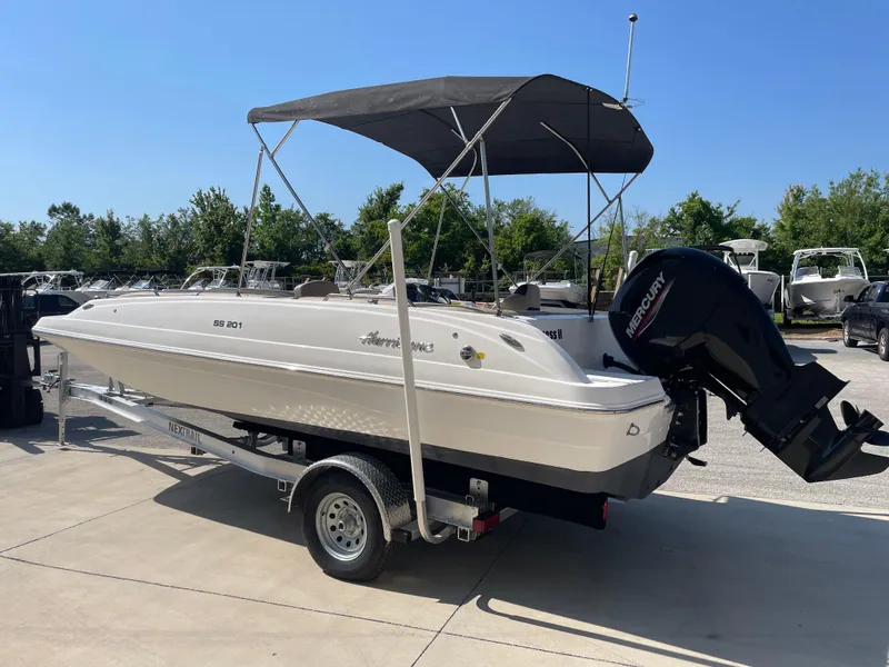 Slide: The Image of 2021 Hurricane SunDeck Sport 201 OB boat on trailer, with canopy, parked outdoors. - 6
