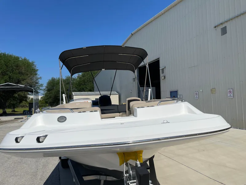 Slide: The Image of 2021 Hurricane SunDeck Sport 201 OB boat with canopy, parked outdoors near a building. - 7