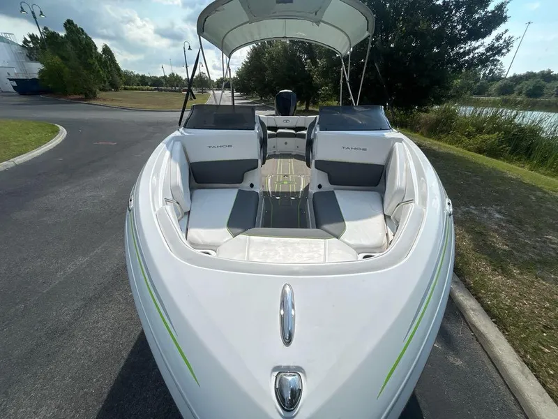 Slide: The Image of 2023 Tahoe 210 S Limited boat with white and green accents, parked on a road near a lake. - 3