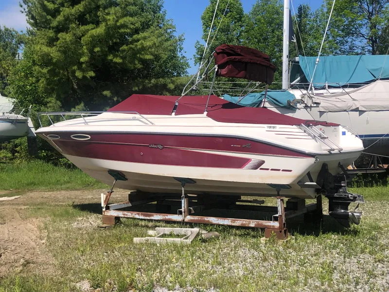 Slide: The Image of 1994 Sea Ray Overnighter boat with maroon cover, parked on a grassy area. - 30