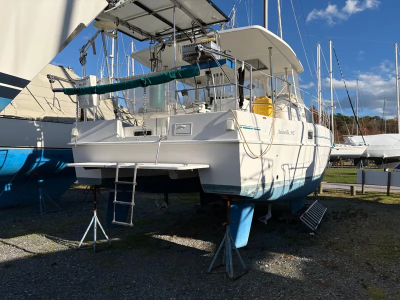 Slide: The Image of 2000 EndeavourCat 36 catamaran on land, with blue sky and other boats in background. - 2