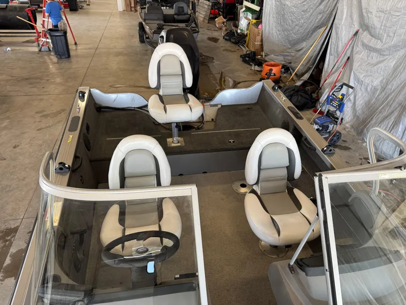 Slide: The Image of 2013 Crestliner 1850 Fish Hawk boat interior with seating and steering wheel in a garage setting. - 13