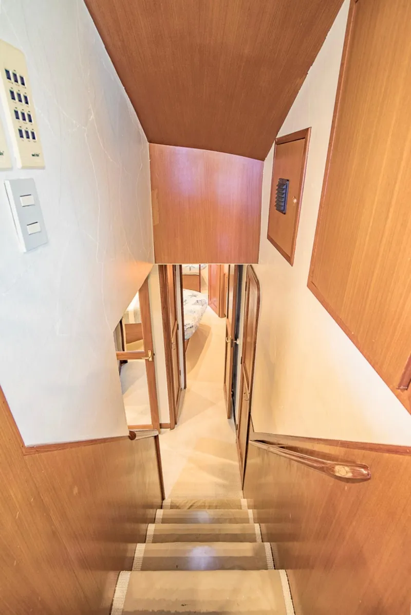 Slide: The Image of Staircase inside 1999 Ocean Yachts 60 Convertible, featuring wooden paneling and compact design. - 15