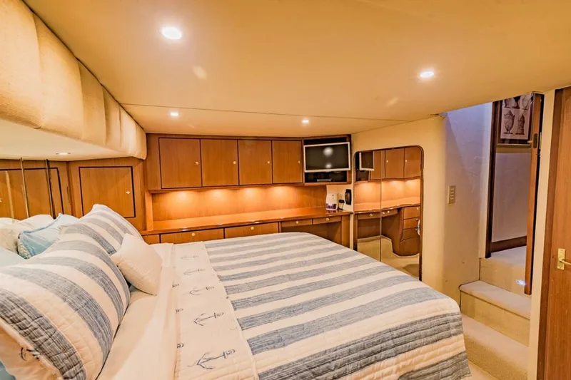 Slide: The Image of Luxurious bedroom interior of 1999 Ocean Yachts 60 Convertible with striped bedding and wood cabinetry. - 16