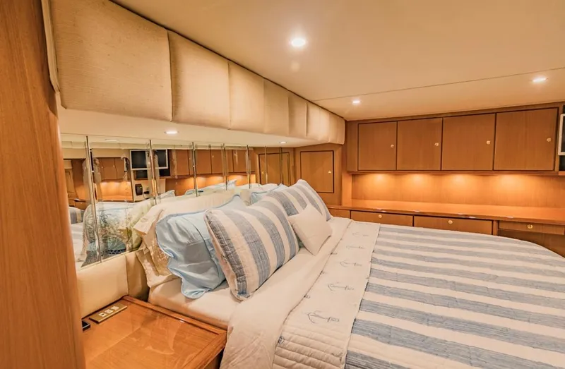Slide: The Image of Luxurious bedroom interior of 1999 Ocean Yachts 60 Convertible with striped bedding and wood cabinetry. - 17