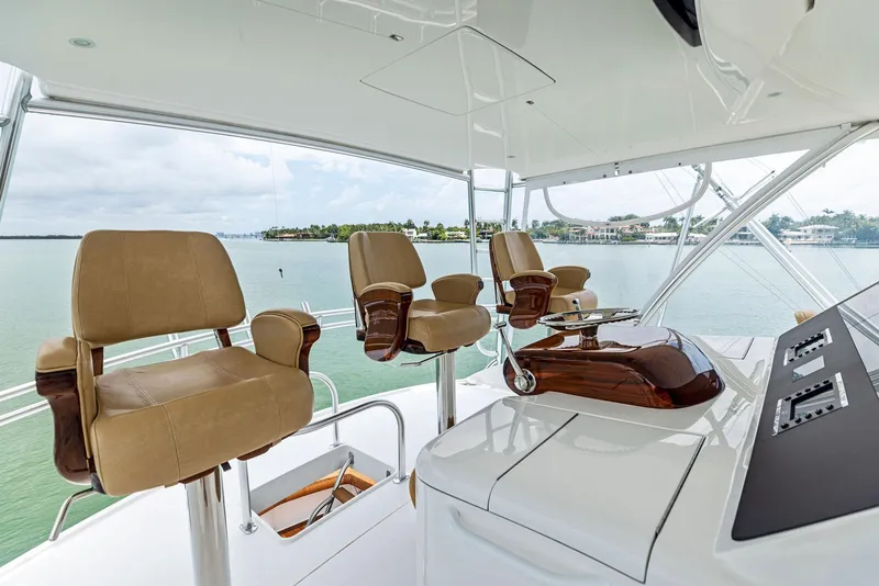 Slide: The Image of Flybridge of 2018 Viking 80 Convertible yacht with beige captain chairs and scenic water view. - 9