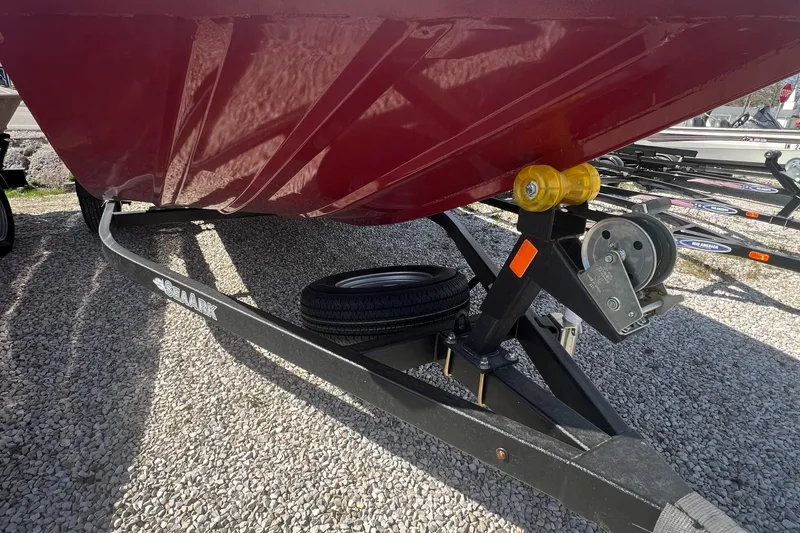 Slide: The Image of 2024 SeaArk 872 RX boat on trailer, showing hull and winch, parked on gravel. - 12