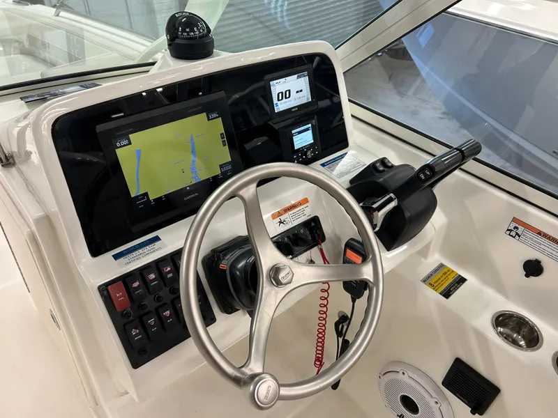 Slide: The Image of 2024 World Cat 230DC boat dashboard with steering wheel, navigation screens, and controls. - 7