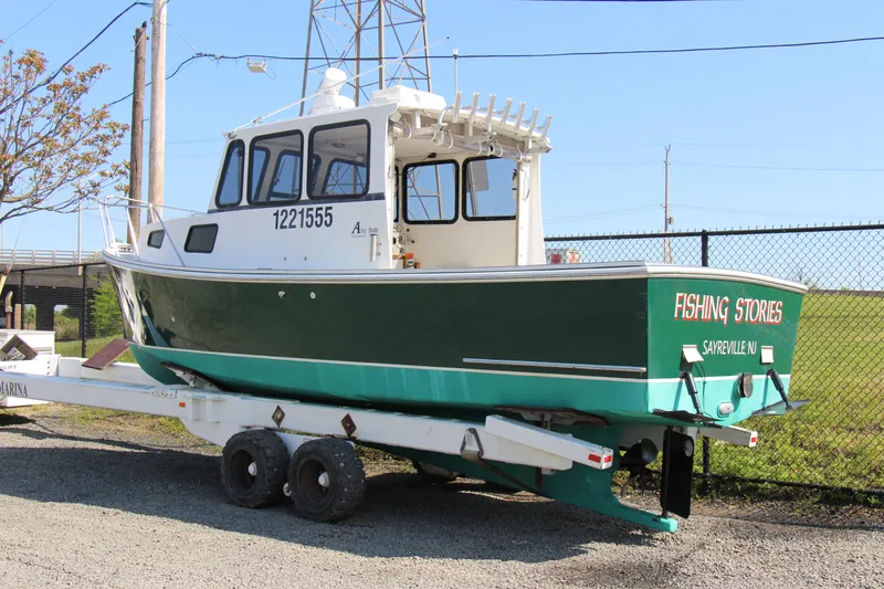Slide: The Image of 2009 Custom Alley Boats 28 Downeast on trailer, green hull, Fishing Stories on stern. - 4