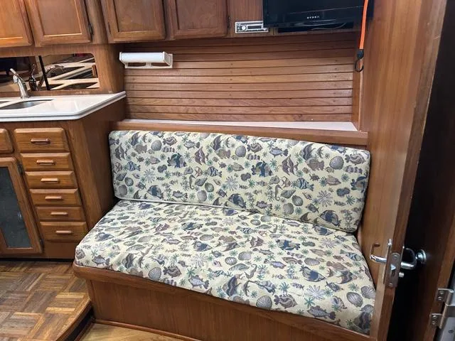 Slide: The Image of 1996 Luhrs 38 Open interior with floral-patterned bench, wooden cabinets, and kitchenette. - 12