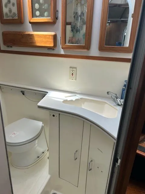 Slide: The Image of 1996 Luhrs 38 Open boat bathroom with sink, toilet, and wooden cabinets. - 15