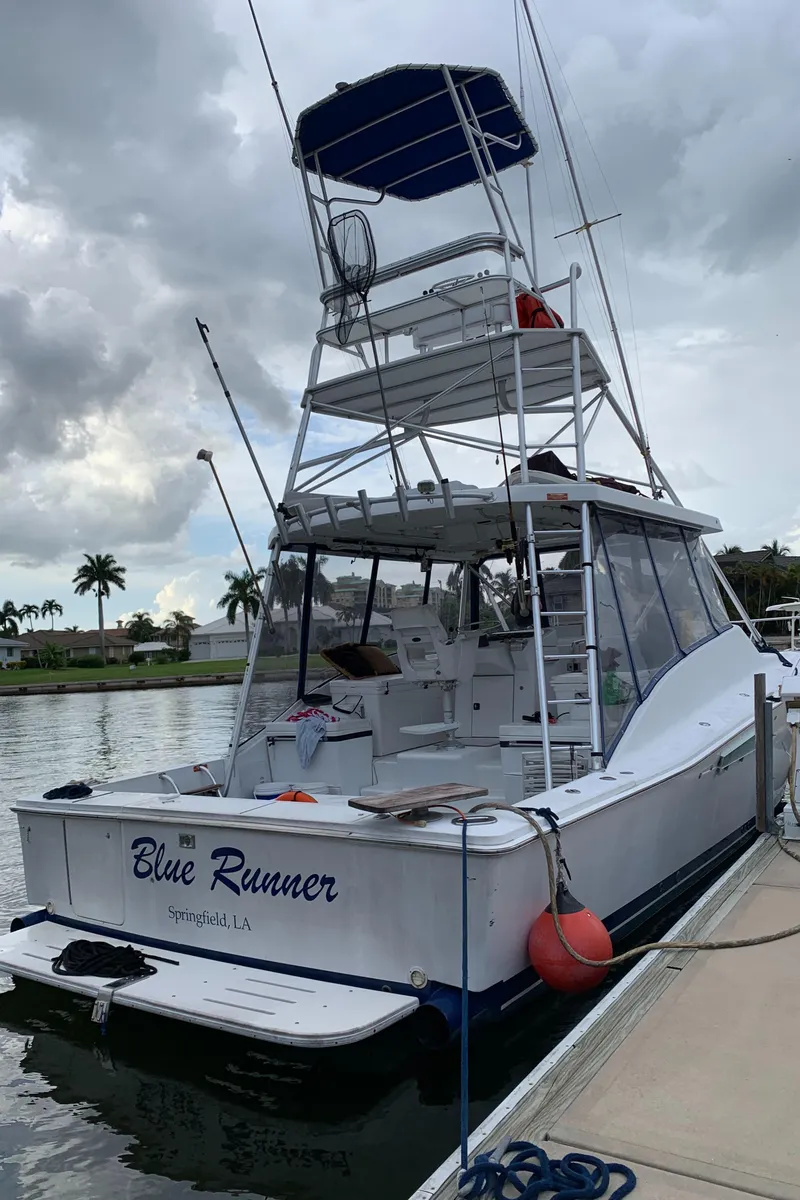 Slide: The Image of 1996 Luhrs 38 Open boat docked, named Blue Runner, with a tower and blue canopy. - 2