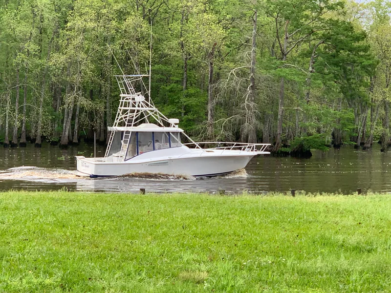 Slide: The Image of 1996 Luhrs 38 Open boat cruising on a river surrounded by lush green trees. - 5