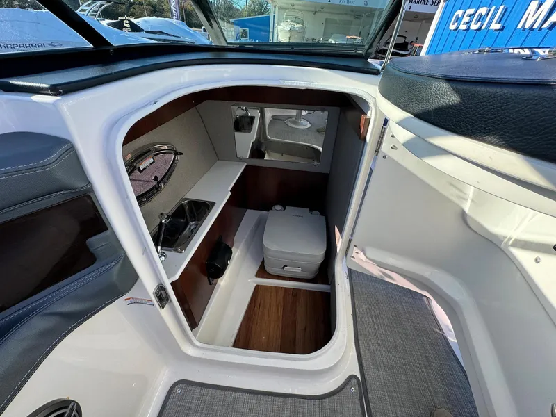 Slide: The Image of 2020 Chaparral 257 SSX boat interior with compact bathroom and storage area. - 13