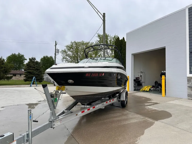 The Image of 2014 Crownline 255 SS boat on a trailer outside a garage. - 0