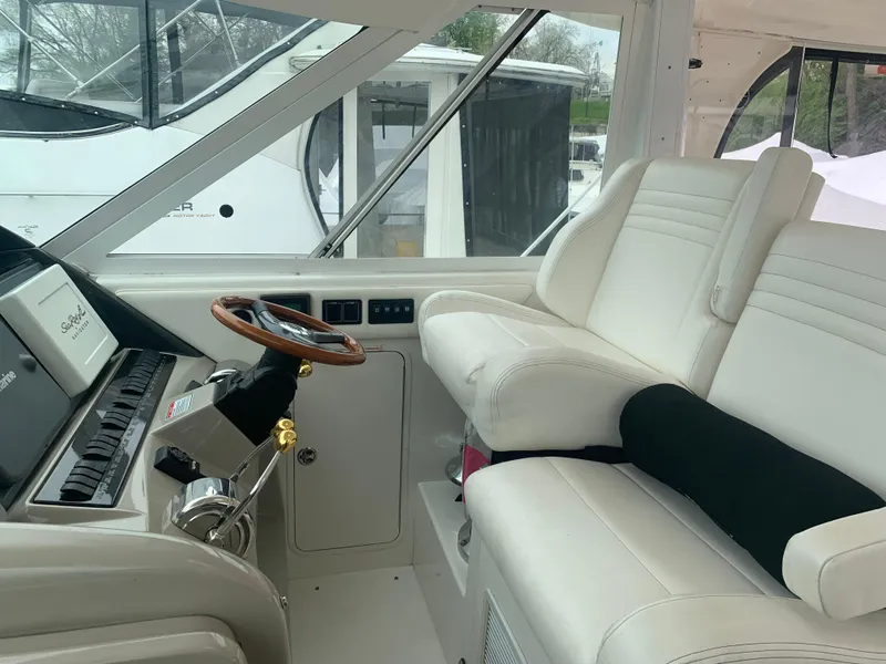 Slide: The Image of 2005 Sea Ray 390 Motor Yacht helm with white leather seats and wooden steering wheel. - 9