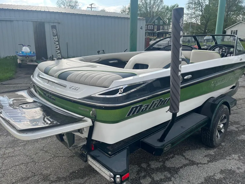 Slide: The Image of 2014 Malibu Response TXi boat with green and white detailing on a trailer. - 3