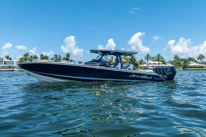 Slide: The Image of 2024 Nor-Tech 400 Supersport boat cruising on a sunny day with palm trees in the background. - 14