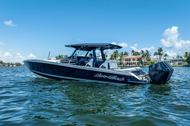 Slide: The Image of 2024 Nor-Tech 400 Supersport boat cruising on a sunny day, with waterfront homes in the background. - 15