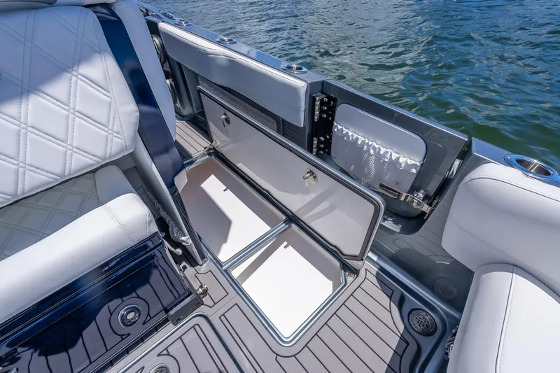 Slide: The Image of 2024 Nor-Tech 400 Supersport boat interior with open storage compartment, white seating, and water view. - 26