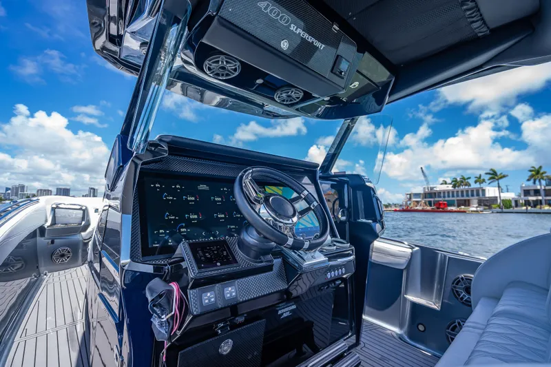 Slide: The Image of 2024 Nor-Tech 400 Supersport boat dashboard with advanced controls, steering wheel, and waterfront view. - 43
