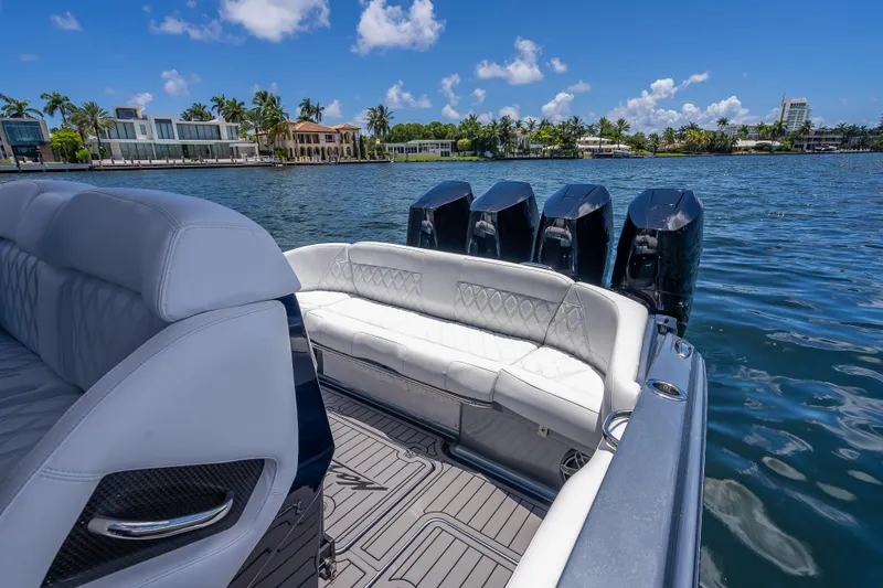 Slide: The Image of 2024 Nor-Tech 400 Supersport boat with luxurious seating and powerful engines on a sunny waterfront. - 49