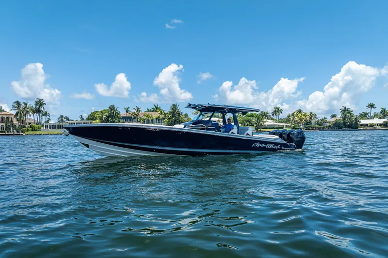 Slide: The Image of 2024 Nor-Tech 400 Supersport boat cruising on a sunny day with palm trees in the background. - 7