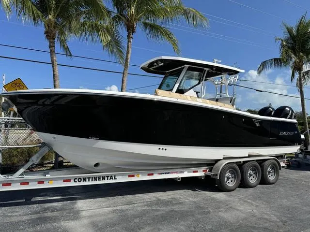 Slide: The Image of 2023 Blackfin 302CC boat on a Continental trailer, parked under palm trees. - 1