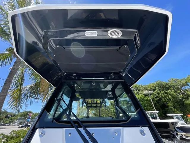 Slide: The Image of 2023 Blackfin 302CC boat with T-top and windshield, palm trees in background. - 19