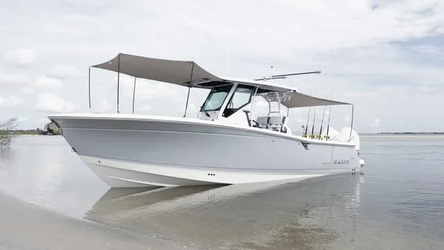 Slide: The Image of 2023 Blackfin 302CC boat anchored on a sandy shore with sunshades. - 42