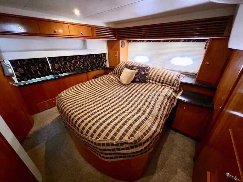 Slide: The Image of 2002 Carver 396 Motor Yacht bedroom with cozy bed and wooden cabinetry. - 23