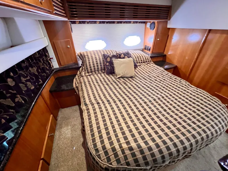 Slide: The Image of 2002 Carver 396 Motor Yacht bedroom with checkered bedding and wooden cabinetry. - 24