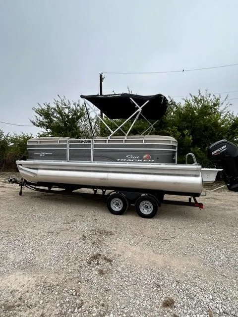 The Image of 2024 Sun Tracker Party Barge 20 DLX pontoon boat on trailer, parked outdoors. - 0