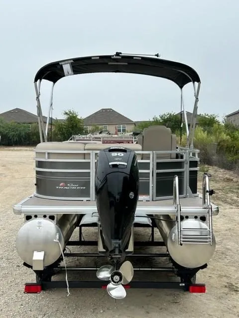 Slide: The Image of 2024 Sun Tracker Party Barge 20 DLX pontoon boat with outboard motor, parked on trailer. - 3
