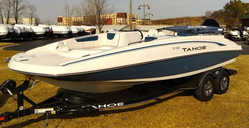 Slide: The Image of 2024 Tahoe 2150 boat on trailer, parked on grass, sunny day. - 0