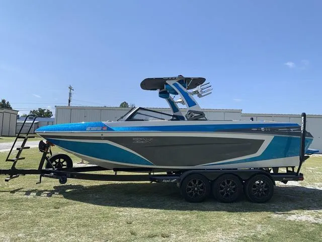 Slide: The Image of 2021 Tigé ZX Class 25 ZX boat on a trailer, blue and gray exterior. - 3