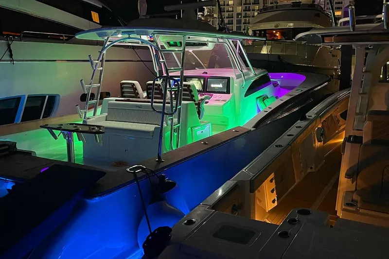 Slide: The Image of 2025 Mystique Boatworks M48 Custom Carolina with vibrant LED lighting at night. - 11
