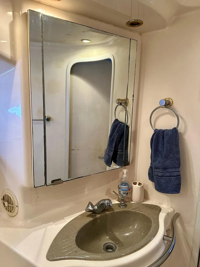 Slide: The Image of Bathroom sink area in a 1998 Maxum 4600 SCB yacht, featuring a mirror and towel. - 28