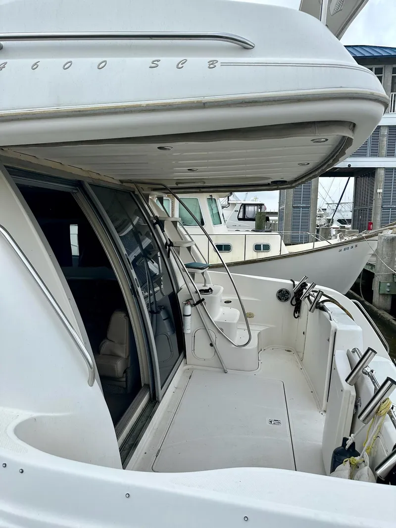 Slide: The Image of 1998 Maxum 4600 SCB yacht docked, showcasing spacious deck and sleek design. - 4