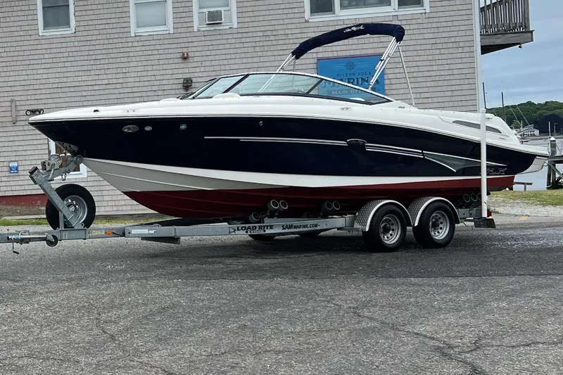 The Image of 2007 Sea Ray 250 SLX boat on a trailer in a marina parking lot. - 1