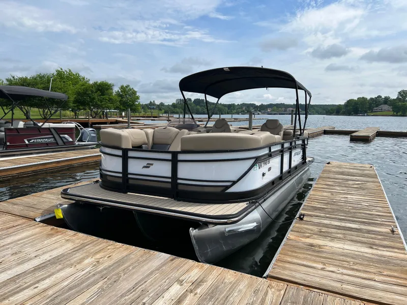 Slide: The Image of 2024 Starcraft SLS 3 pontoon boat docked on a lake. - 1